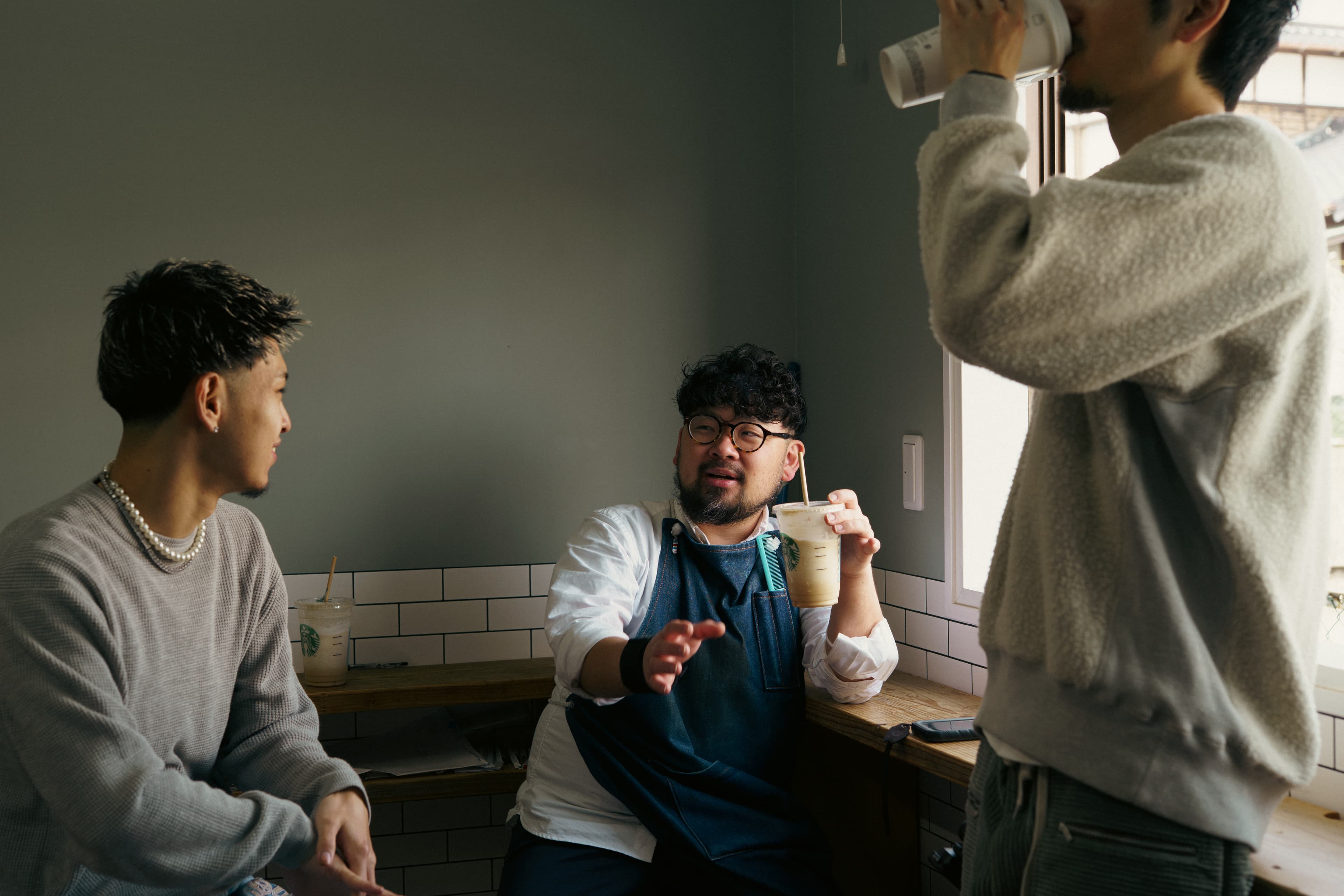 仕事の合間に、コーヒーを片手に会話するスタッフたち